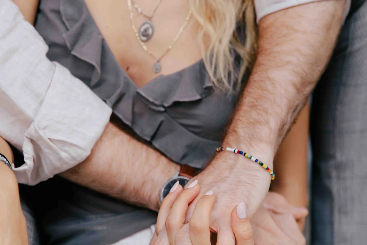 Close-up of a couple embracing, with the woman’s hands resting on her partner’s forearm